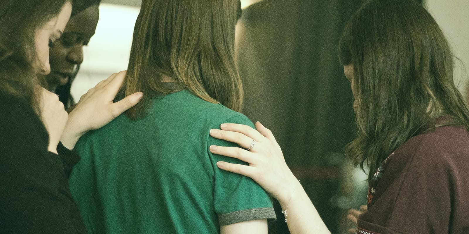 A group of people standing in a supportive circle with their hands on each other's shoulders, symbolizing the support and solidarity in the journey of a PMDD diagnosis.