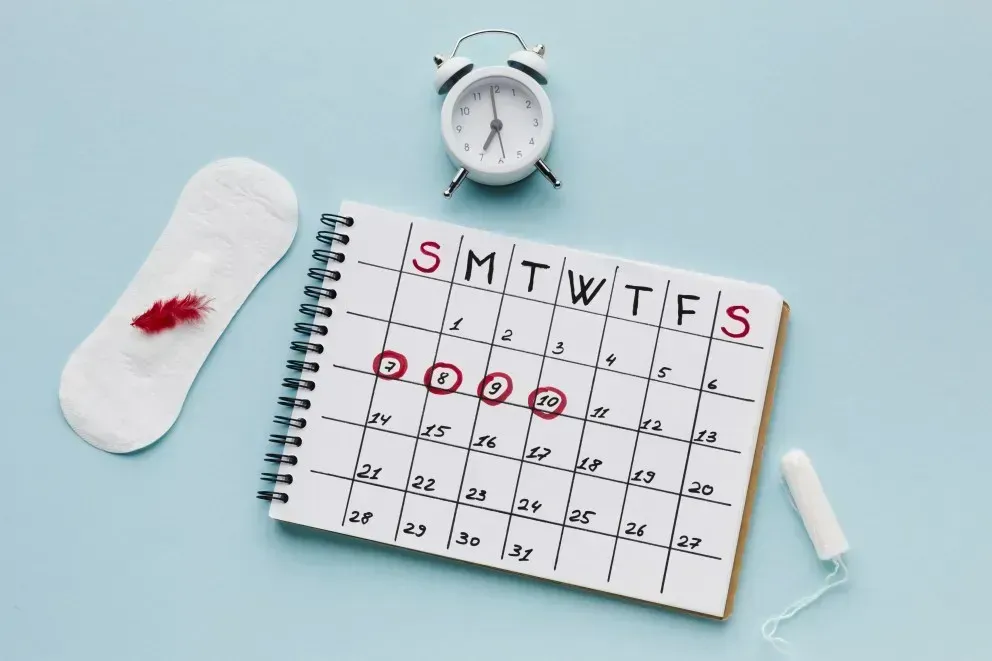 Periode verschieben: Menstruationskalender mit markierten Zyklustagen, Binde, Tampon und Uhr als Symbol für zeitlich geplante Menstruation