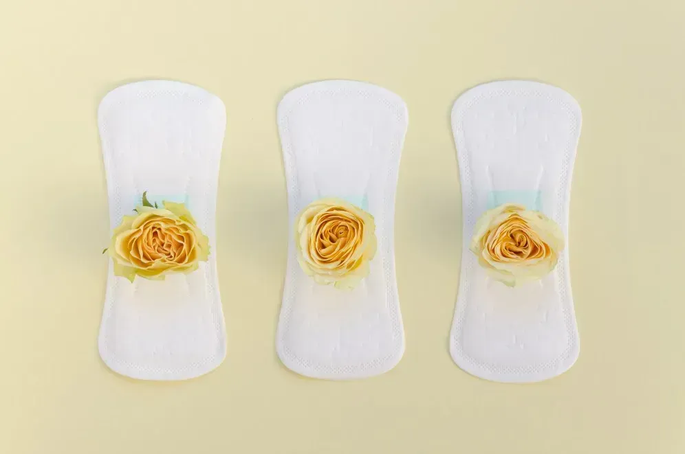 Hygienebinden mit Blumen als Symbol für Ausfluss in den Wechseljahren