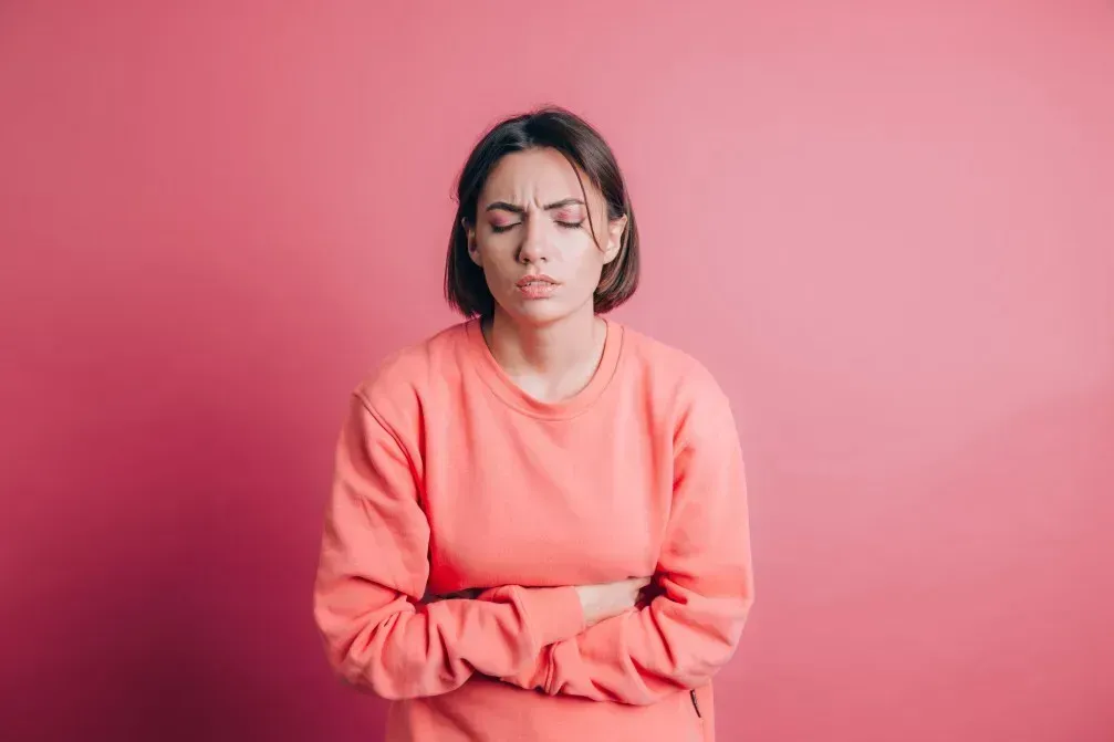 Portrait einer Frau in gekrümmter Haltung mit schmerzverzerrtem Gesicht als Symbol für Übelkeit bei Endometriose