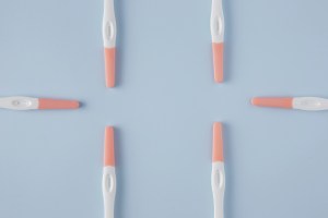 Mehrere Ovulationstests liegen kreisförmig auf blauem Hintergrund – Symbolbild für LH-Anstieg messen und Eisprung bestimmen.