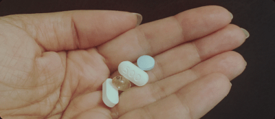 Pokyny pro léčbu PMDD: Ruka držící různé pilulky