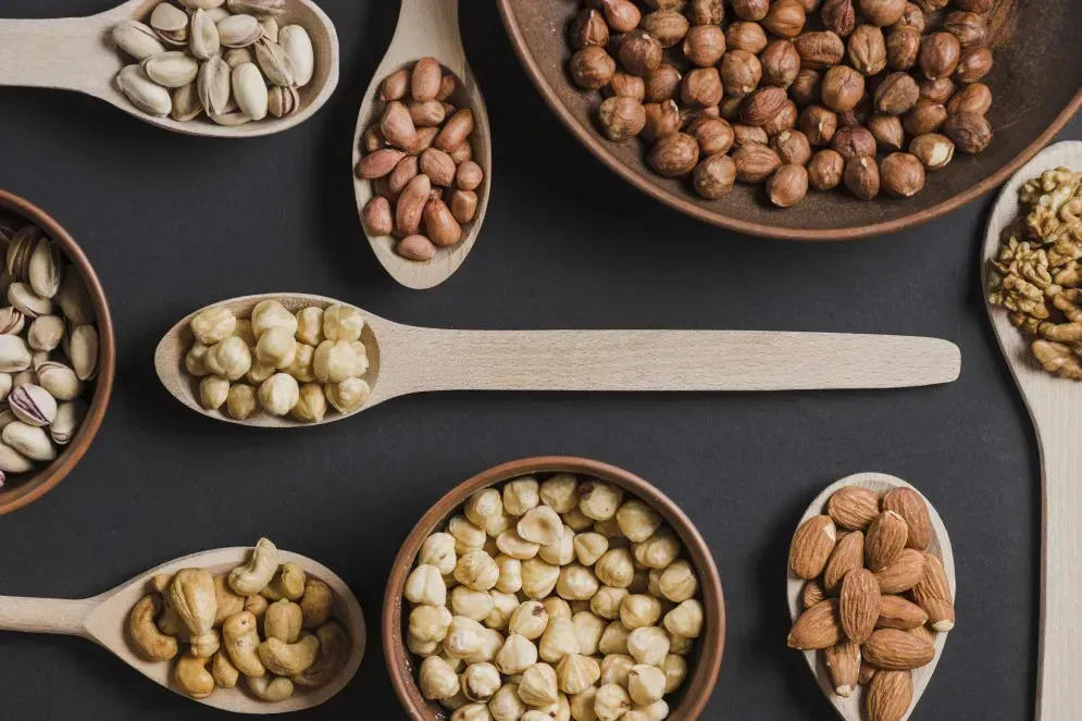 Verschiedene Nüsse und Kerne in Holzlöffeln und Schalen als natürliche Quellen für Vitamin B6 und Zink