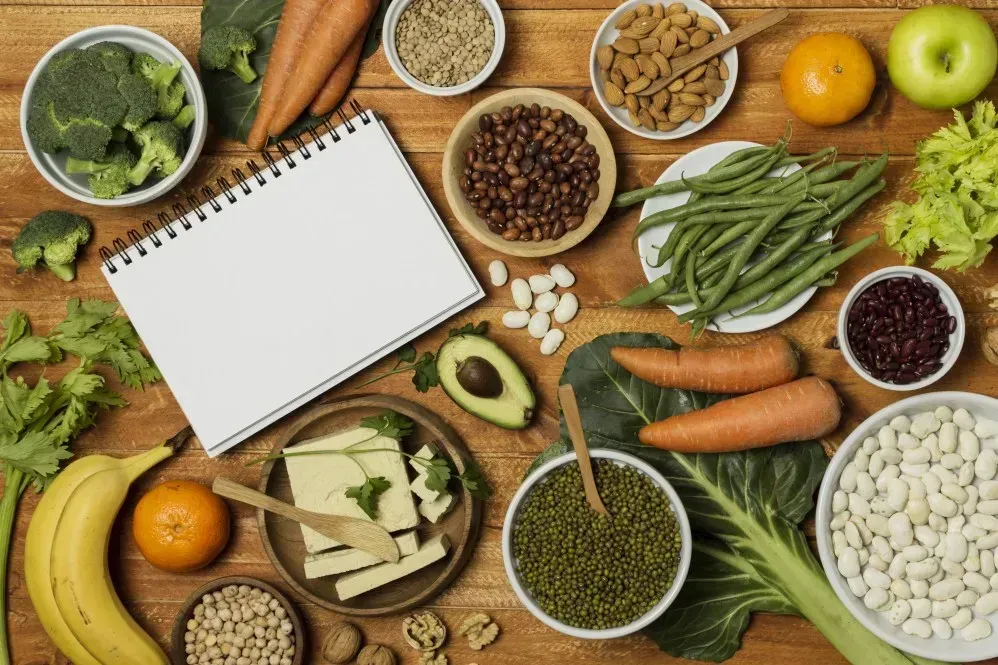 Lebensmittel mit Östrogen wie Hülsenfrüchte, Soja, Brokkoli, Karotten, Nüsse und Obst auf einem Holztisch – Ernährung zur Unterstützung des Östrogenspiegels“