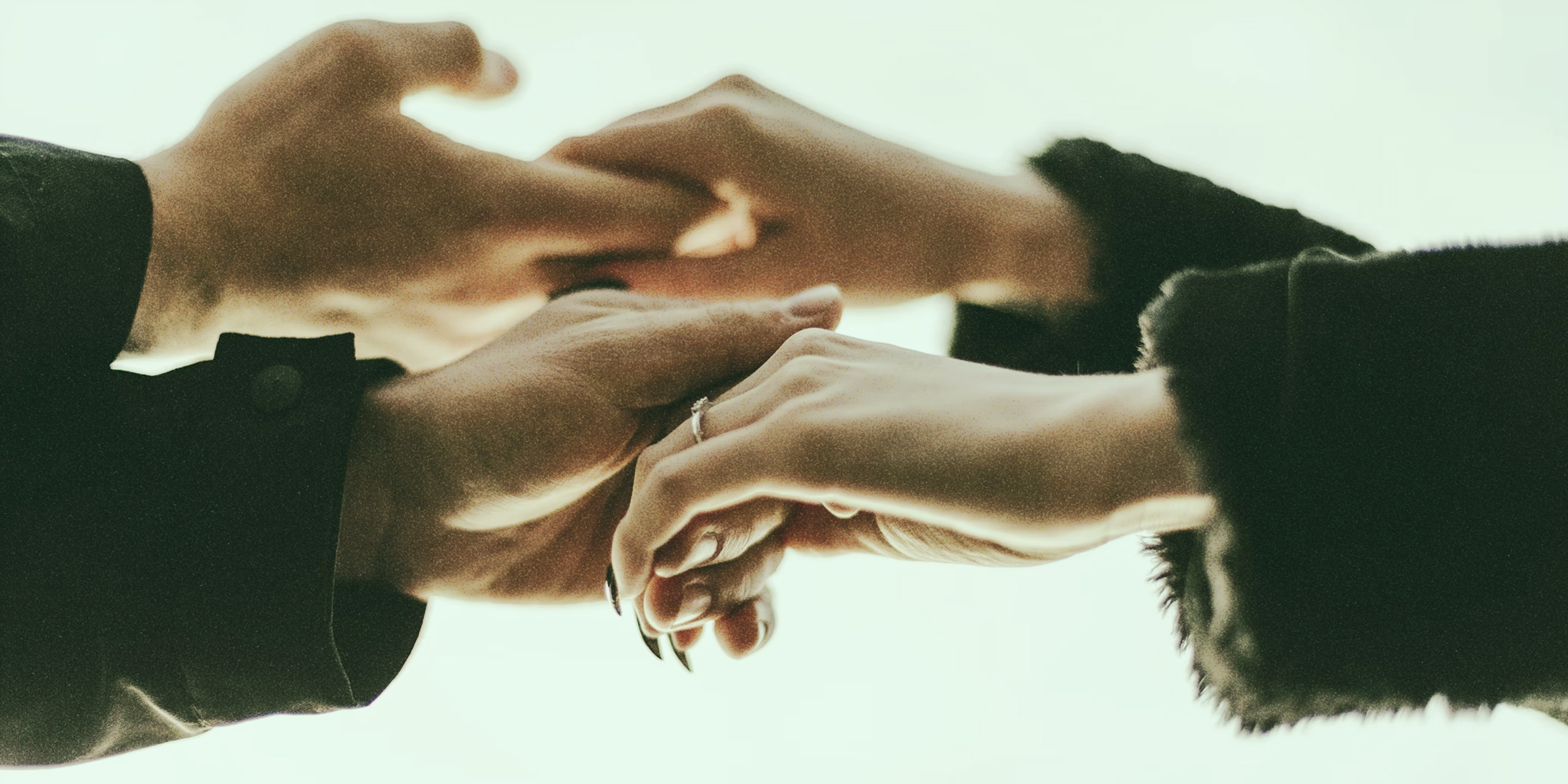 A female hand with a ring holds a male hand, showcasing the support he gives her during PMDD struggles.