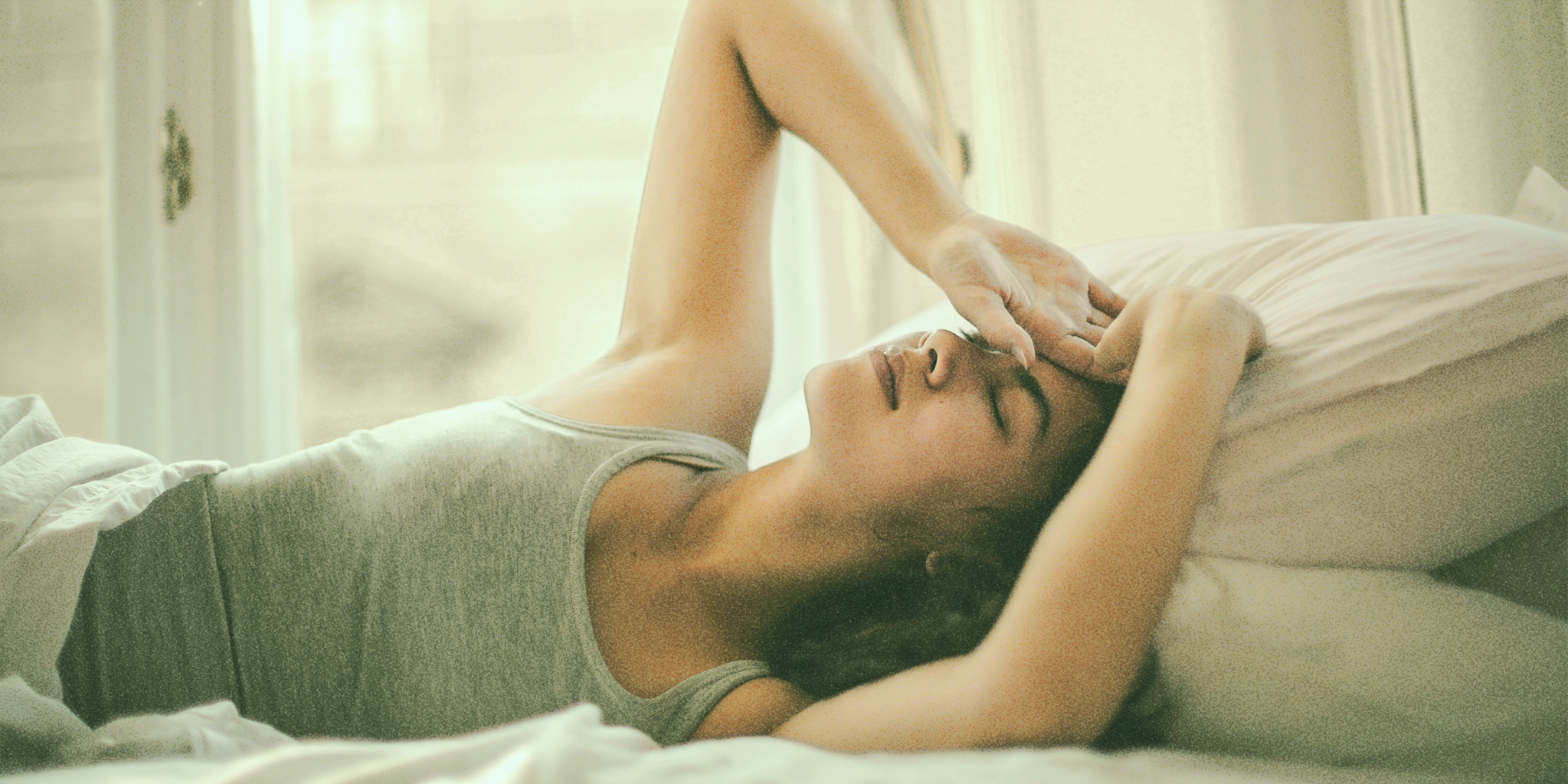 Woman lying in bed experiencing fatigue and emotional sensitivity, common symptoms of mood changes with ovulation.