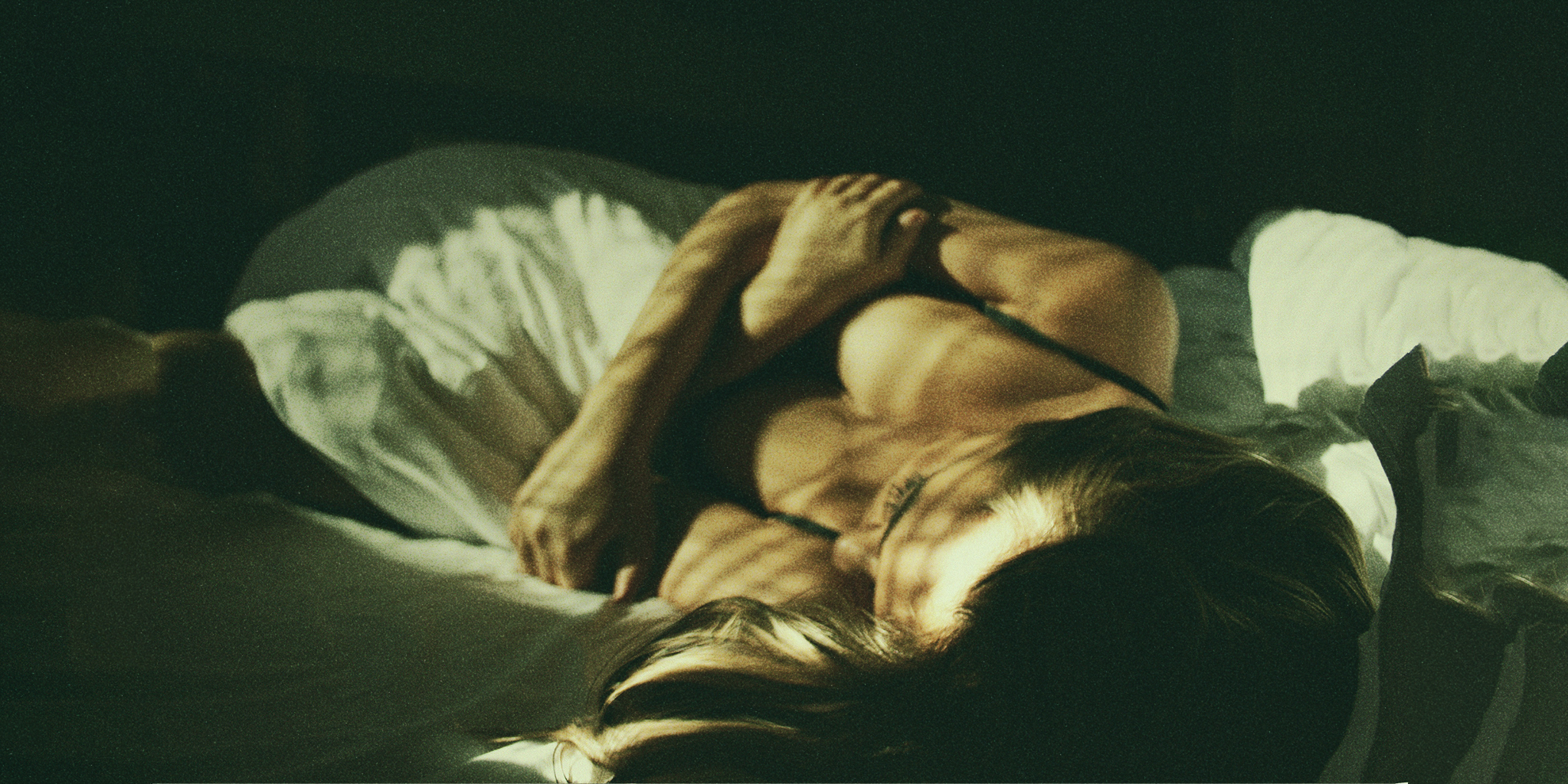 A woman lying in bed with soft natural light casting shadows across her body, symbolizing introspection and the journey of rediscovering libido while on birth control.